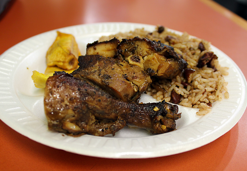 A plate of jerk chicken with rice and peas.