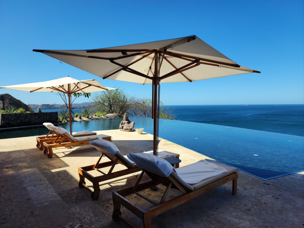 Lounge chairs and a sun umbrella in front an infinity pool